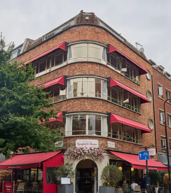 A multi-story brick building with red awnings houses 